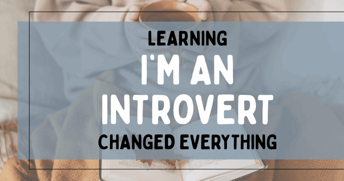 A woman with a cup of cocoa reading a book with a leaf on top of it with the title Learning I’m an Introvert Changed Everything overlaid.